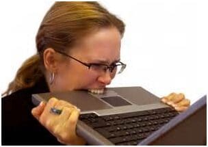 Woman biting laptop in frustration.