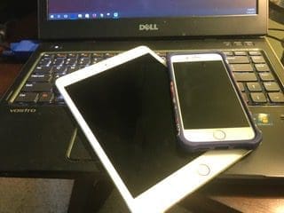 A white tablet and a smartphone on a Dell laptop keyboard.