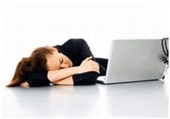 Person asleep beside an open laptop.
