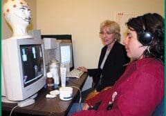 Two women using desktop computers in a room.