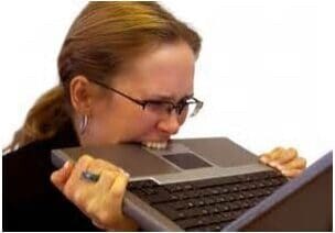 Woman biting laptop in frustration.